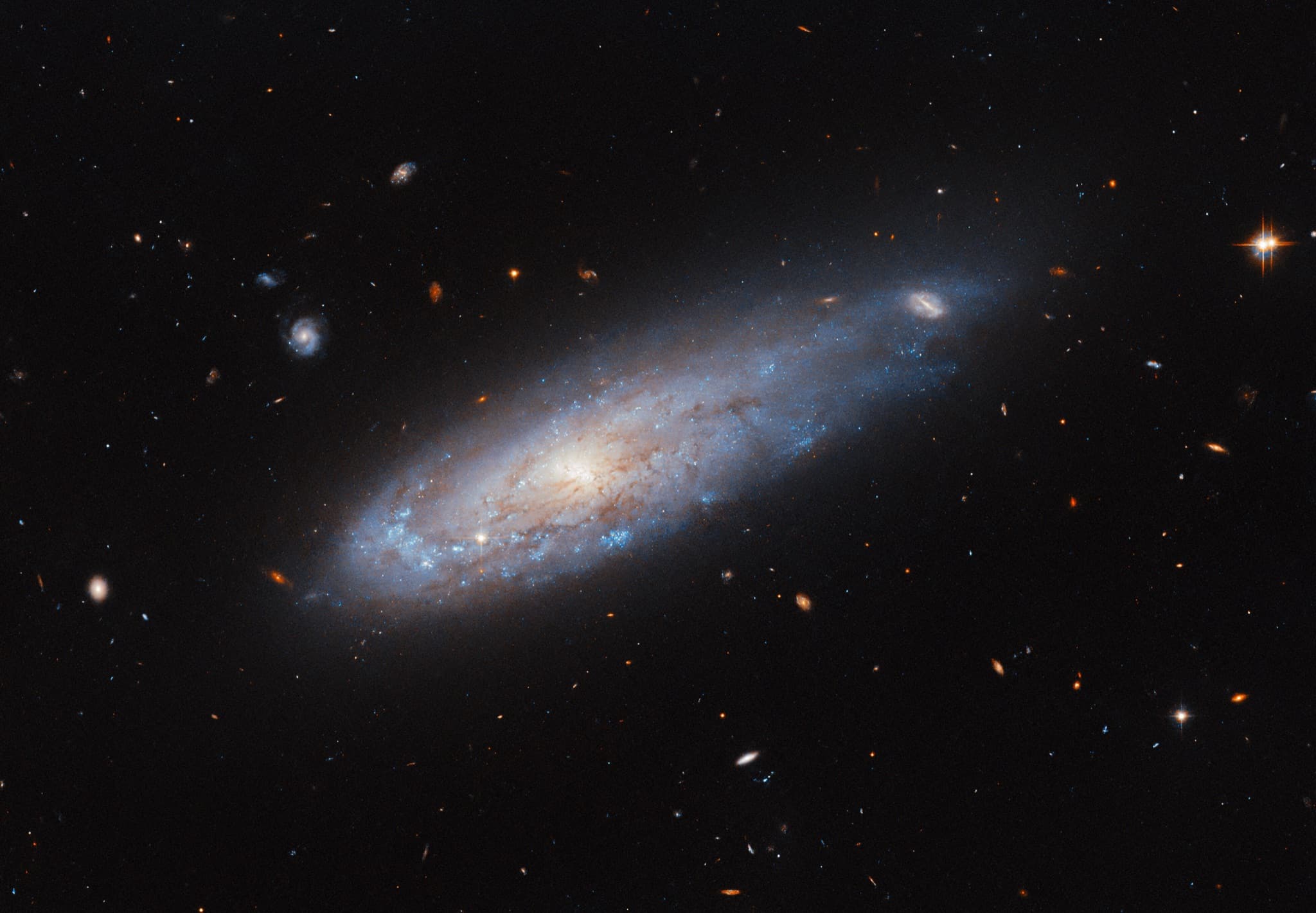The spiral galaxy IC 3225, compressed with bright star formation along its leading edge and a stretched, distorted tail, as if streaking through space like a cannonball.