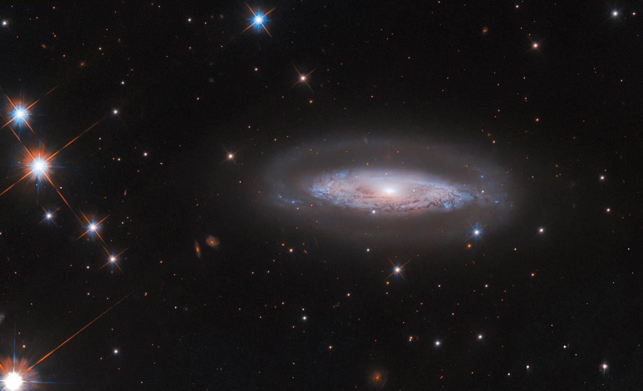 The spiral galaxy IC 4709, a faint halo and swirling disk crossed by a dark dust lane surrounding a bright active galactic nucleus.