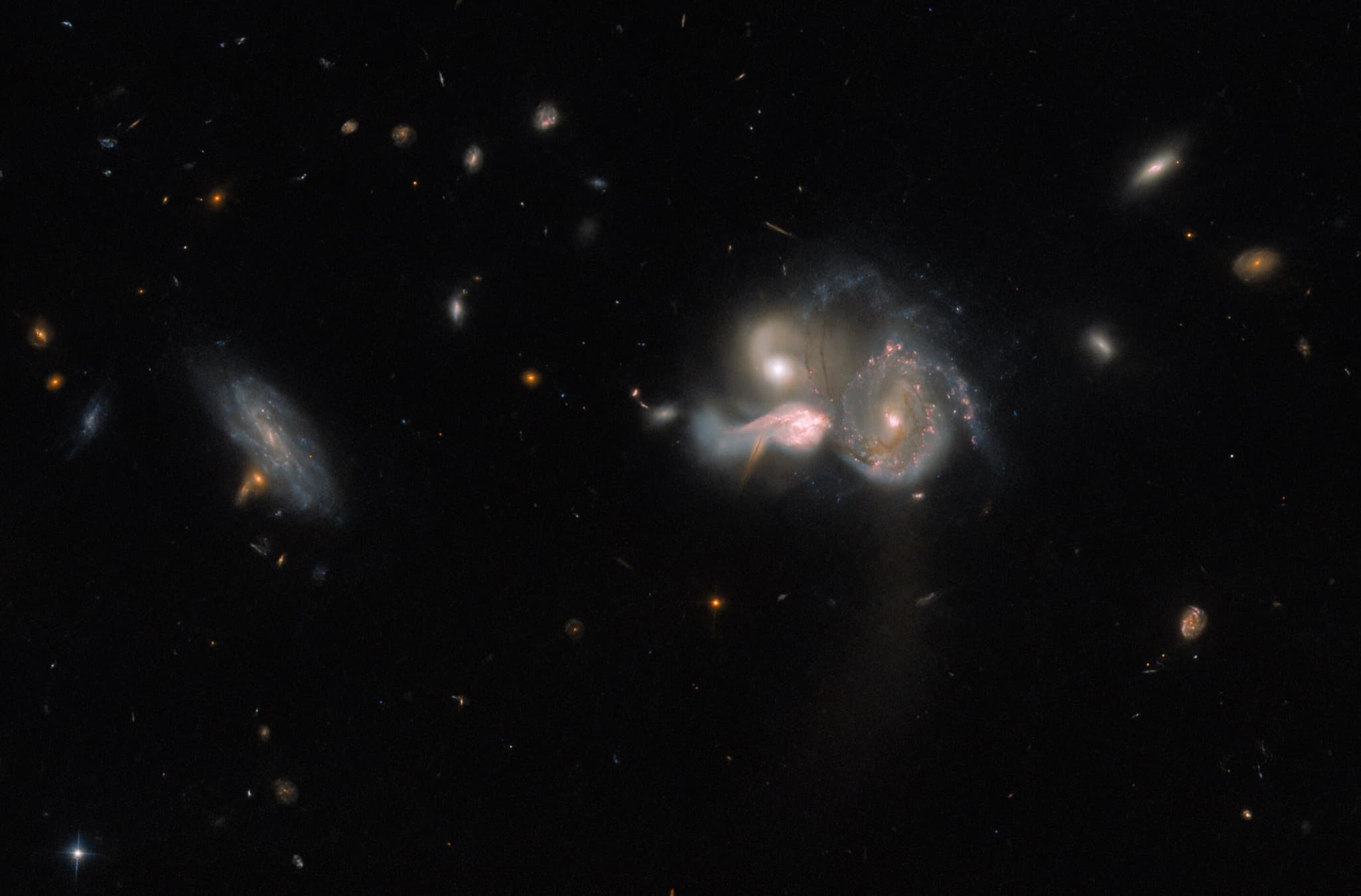 Three star-forming galaxies of the SDSSCGB 10189 group tangled together mid-collision, with fainter, more distant galaxies scattered across the dark background.