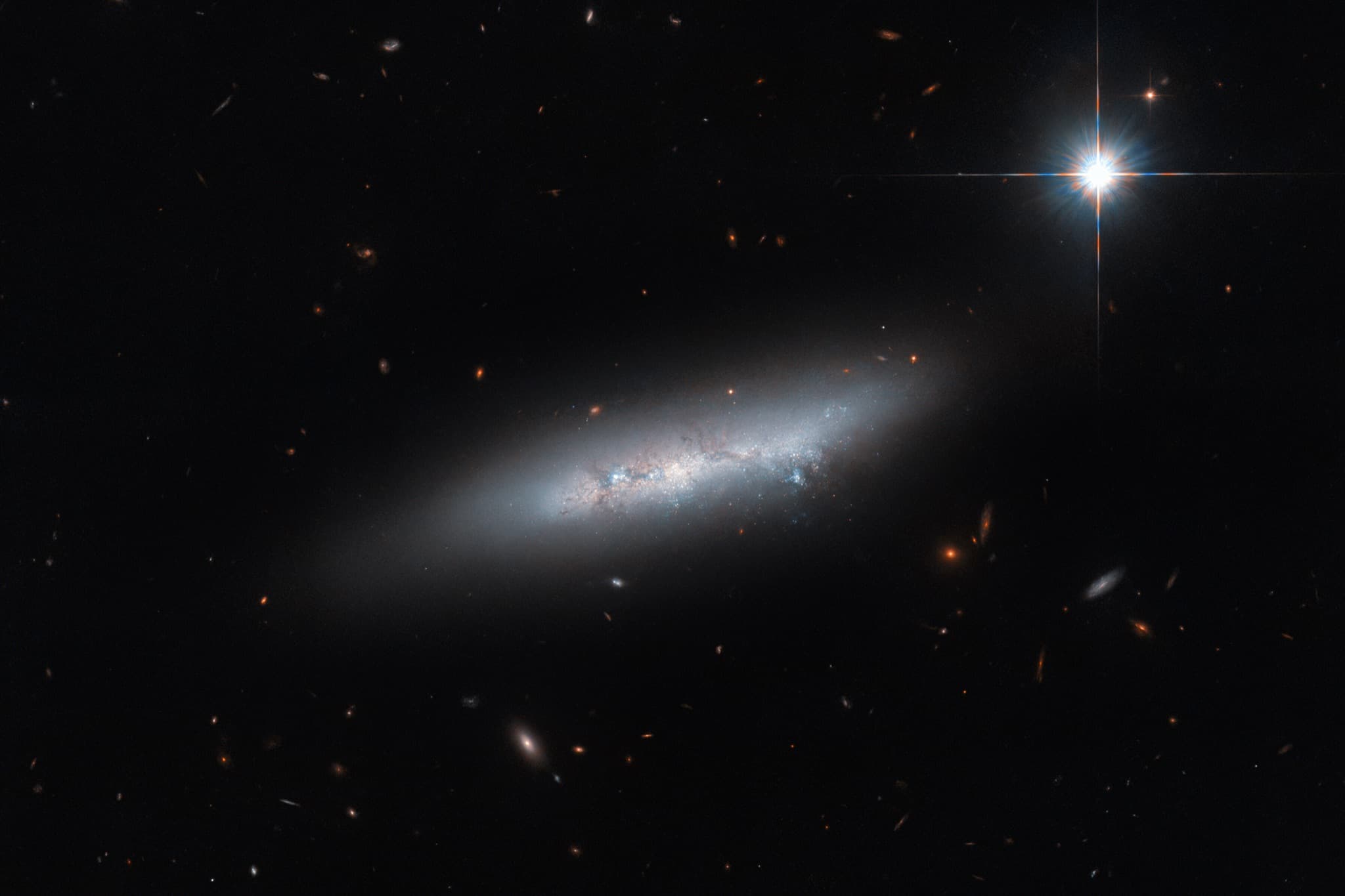 The irregular late-type galaxy NGC 2814 as a thin, edge-on sliver of pale light against a dark, nearly empty field.