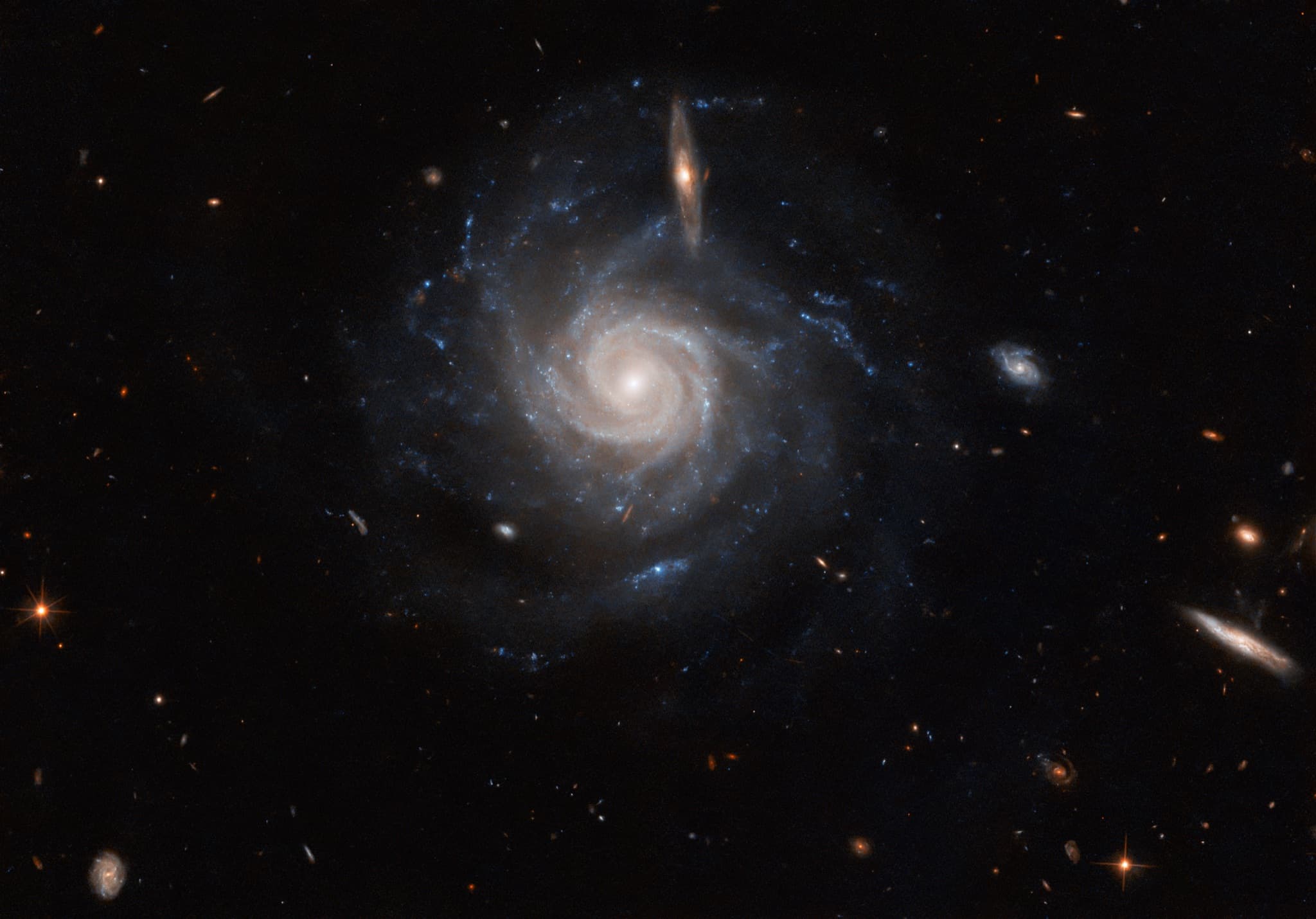 The barred spiral galaxy UGC 678 seen nearly face-on with softly winding spiral arms, its faint bar crossed in the foreground by a smaller edge-on galaxy.