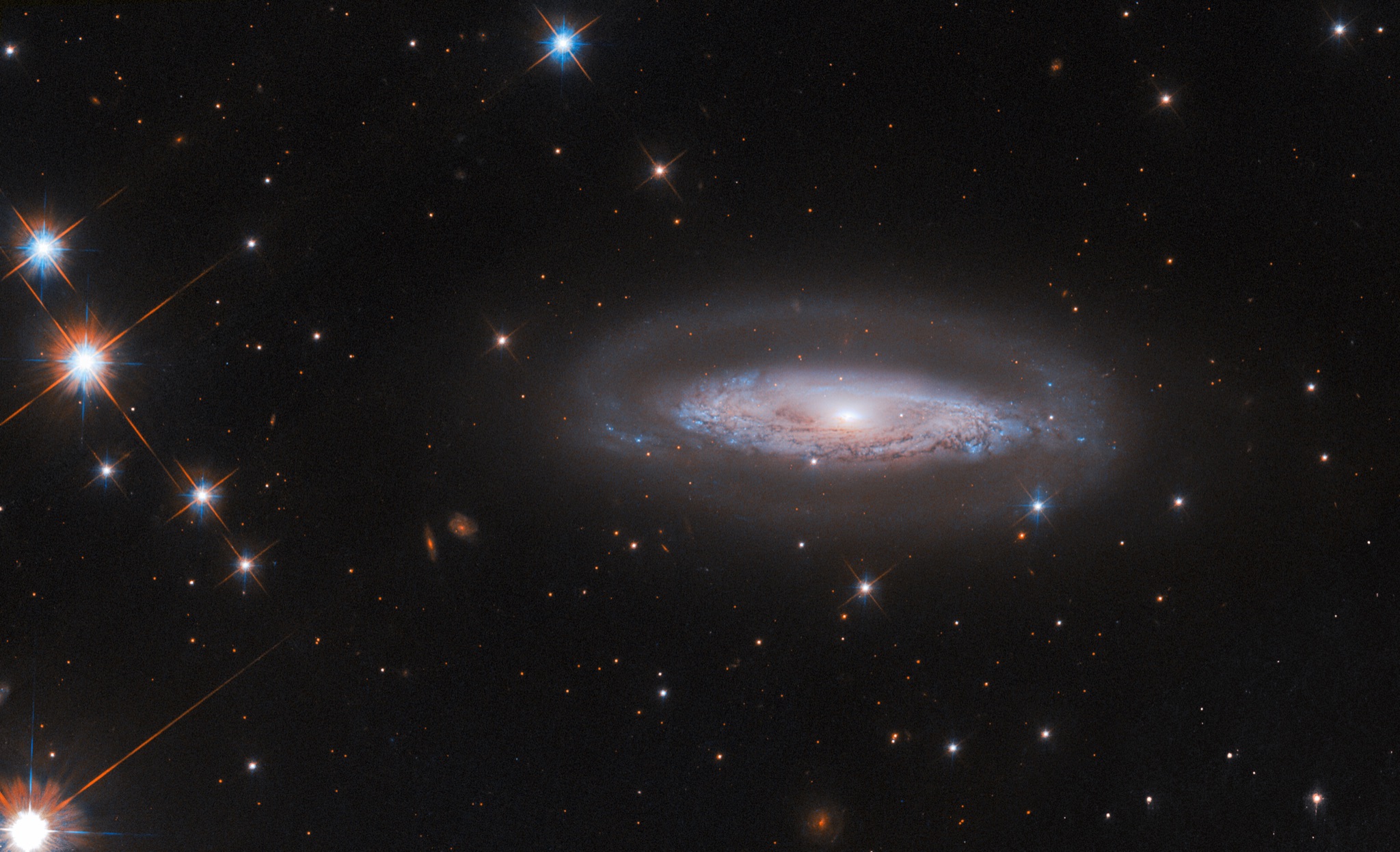 The spiral galaxy IC 4709, a faint halo and swirling disk crossed by a dark dust lane surrounding a bright active galactic nucleus.