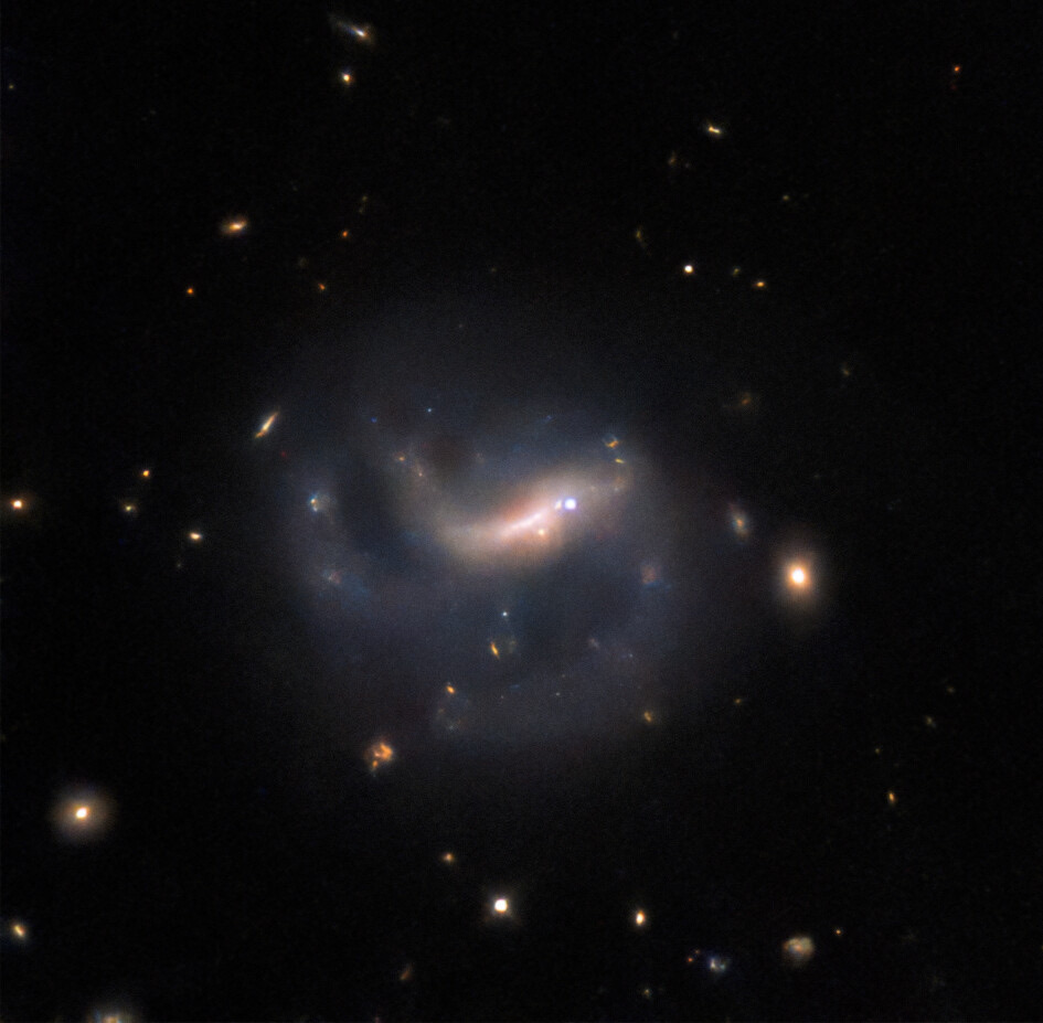 The barred spiral galaxy LEDA 857074 against the dark of space, with the bright point of a supernova shining on the right side of the galaxy's central bar.