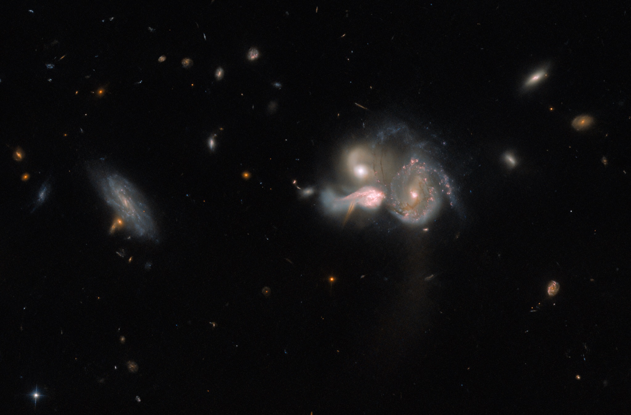 Three star-forming galaxies of the SDSSCGB 10189 group tangled together mid-collision, with fainter, more distant galaxies scattered across the dark background.
