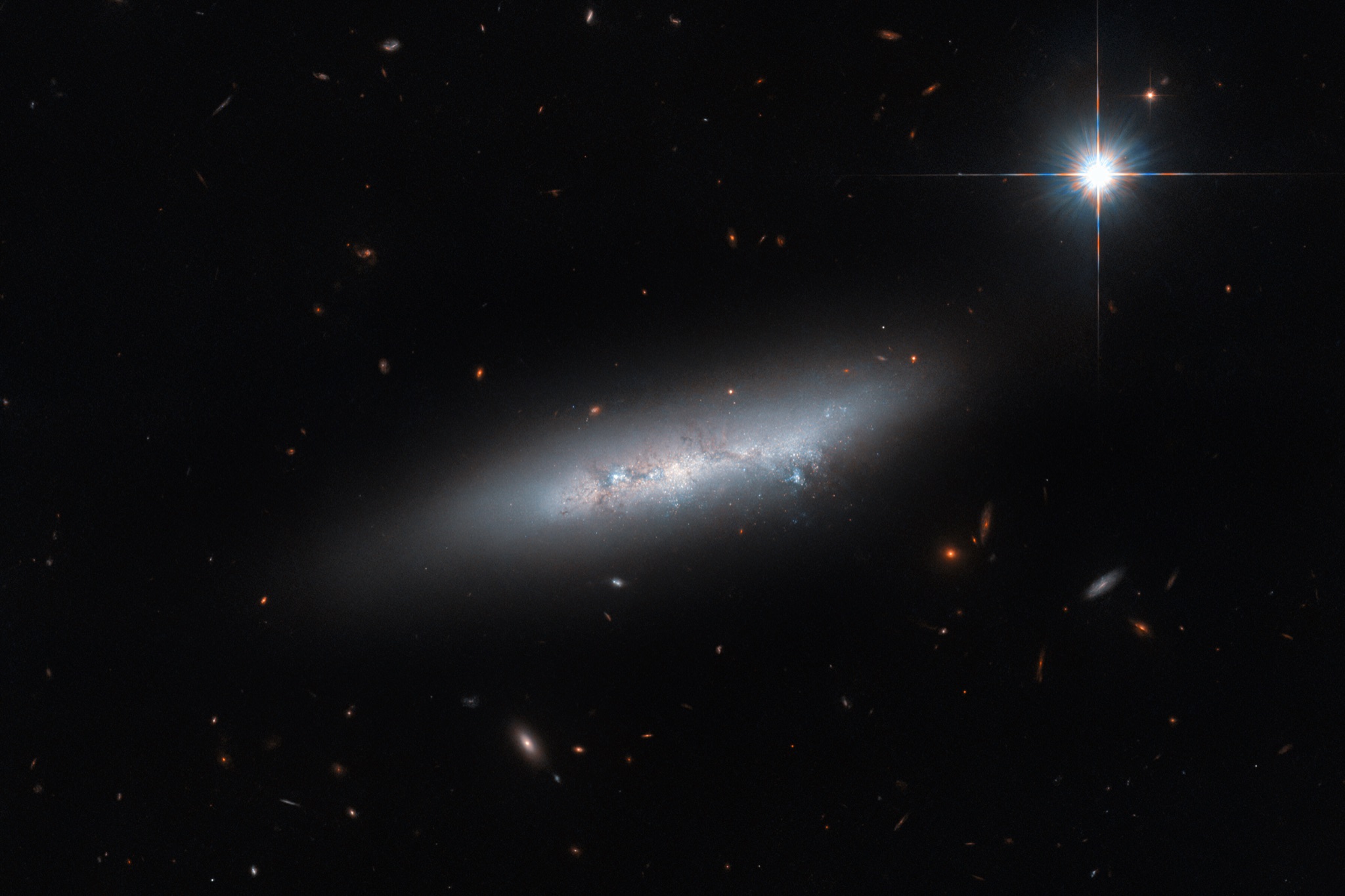 The irregular late-type galaxy NGC 2814 as a thin, edge-on sliver of pale light against a dark, nearly empty field.