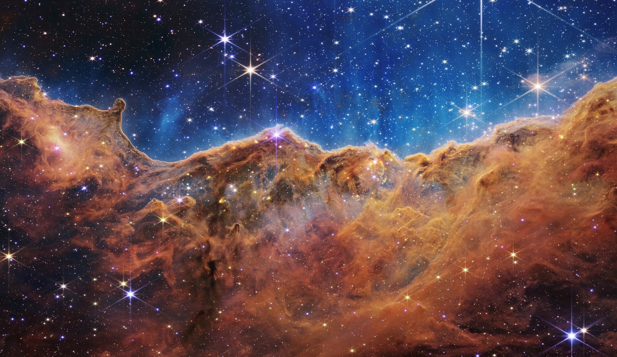 The Cosmic Cliffs of NGC 3324, a ridge of gas and dust glowing against young stars.