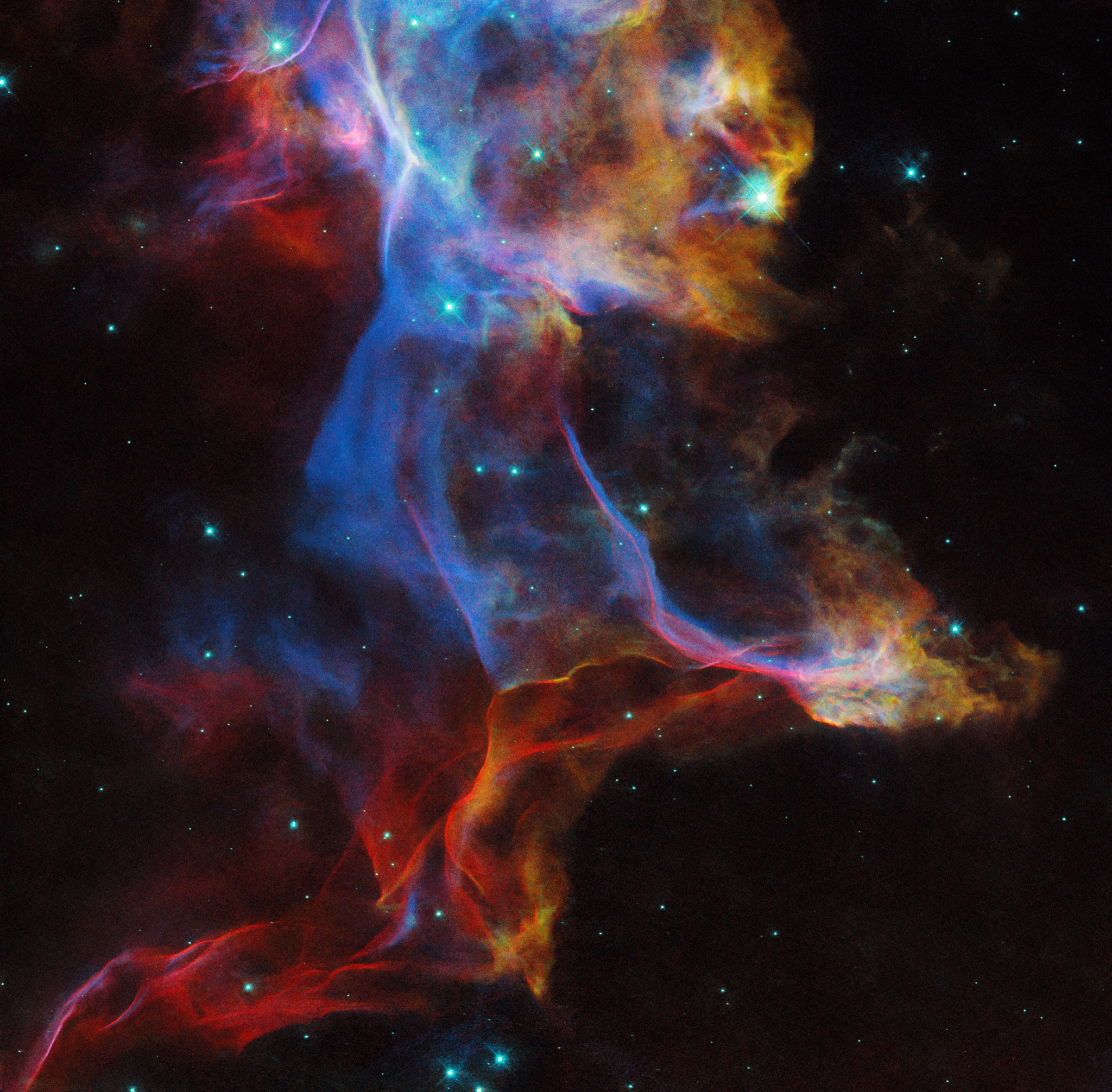 Delicate, wispy ribbons of red, blue, and gold filaments from the Veil Nebula supernova remnant stretching across a star-filled field.